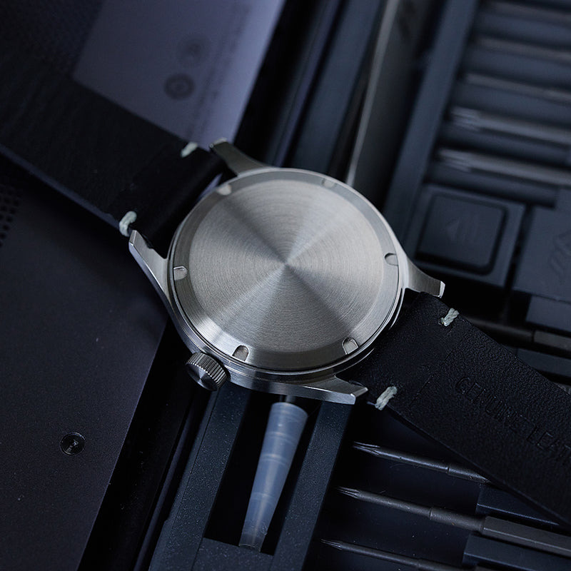 M059 watch with brushed case back, lying face down on a screw toolbox