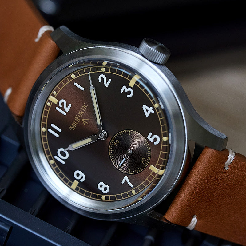 Brown dial field watch lying sideways on a tool box