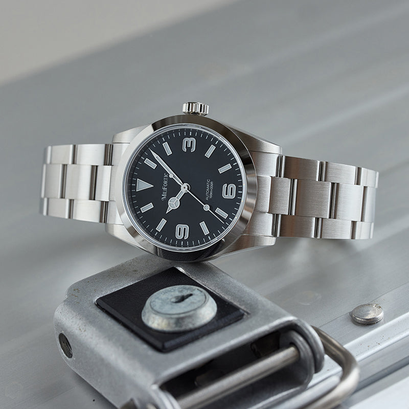 Stainless steel watch lying horizontally on a stainless steel block