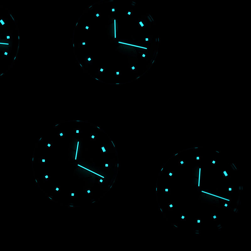 Four watches glowing in the dark, displaying blue-green luminous hands and markers.
